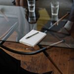 White and Silver Chair Beside Clear Drinking Glass on Glass Table